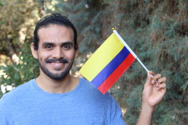 Parkta Kolombiya bayrağı taşıyan yakışıklı bir gencin portresi.