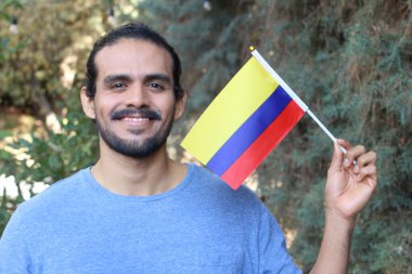 Parkta Kolombiya bayrağı taşıyan yakışıklı bir gencin portresi.