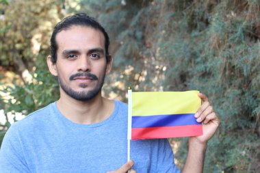 Parkta Kolombiya bayrağı taşıyan yakışıklı bir gencin portresi.