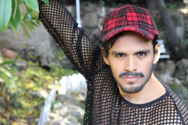 Ağ gömlekli ve açık havada kırmızı şapkalı yakışıklı bir adamın yakın plan portresi.