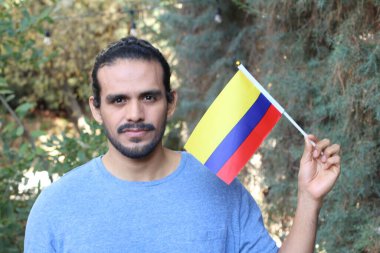 Parkta Kolombiya bayrağı taşıyan yakışıklı bir gencin portresi.