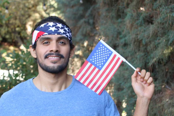 Parkta Amerikan bayrağı ve bandosu olan yakışıklı bir gencin portresi.