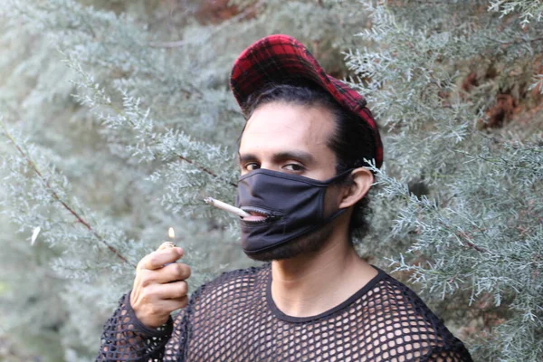ネットシャツを着たハンサムな青年と屋外でタバコを吸うマスクの肖像画 — ストック写真