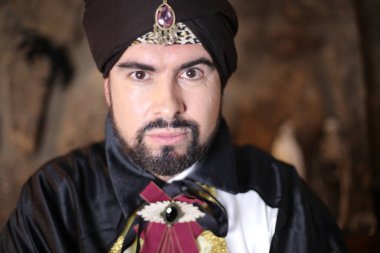 Sihirbaz kıyafetleri içindeki Müslüman sakallı adamın yakın plan portresi.