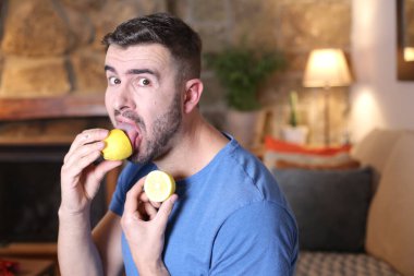 Evde ekşi limon yalayan yakışıklı bir gencin portresi.