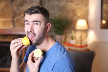 Evde ekşi limon yalayan yakışıklı bir gencin portresi.