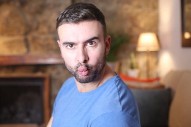 Yakışıklı genç adam evde yüzünü ekşitiyor.