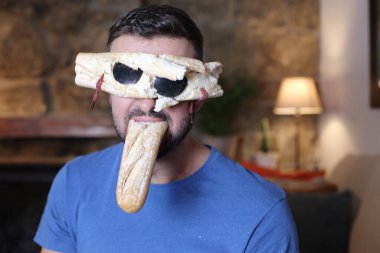 Ekmek gözlüklü yakışıklı genç bir adam. Ağzında baget var.