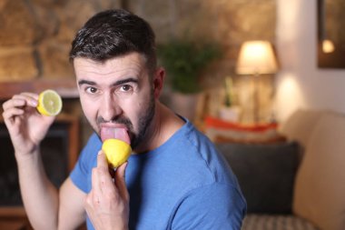 Evde ekşi limon yalayan yakışıklı bir gencin portresi.