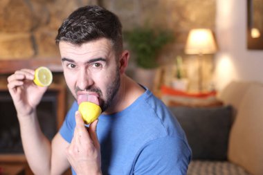 Evde ekşi limon yalayan yakışıklı bir gencin portresi.