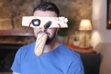 Ekmek gözlüklü yakışıklı genç bir adam. Ağzında baget var.