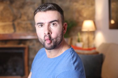 Yakışıklı genç adam evde yüzünü ekşitiyor.