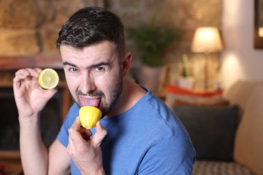 Evde ekşi limon yalayan yakışıklı bir gencin portresi.