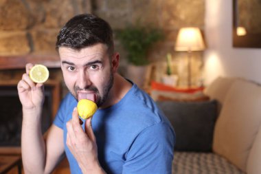 Evde ekşi limon yalayan yakışıklı bir gencin portresi.
