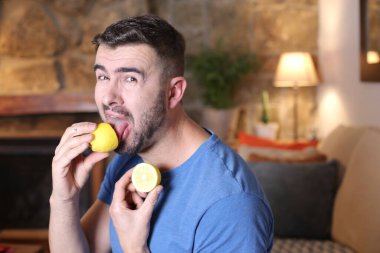 Evde ekşi limon yalayan yakışıklı bir gencin portresi.