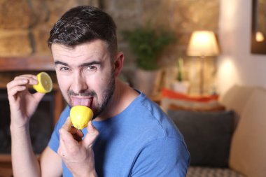 Evde ekşi limon yalayan yakışıklı bir gencin portresi.