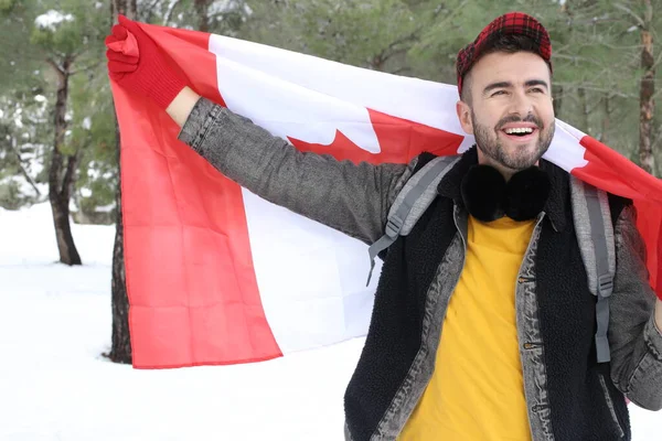 在冬季森林中高举加拿大国旗的英俊年轻人 — 图库照片