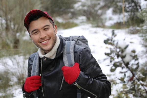 handsome young man in leather jacket with backpack in winter forest