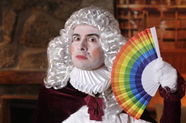 Viktorya tarzı kostümlü genç adam elinde lgbtq renkli yelpaze tutuyor.