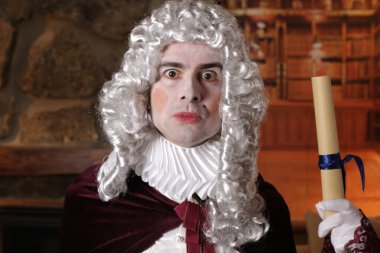 Viktorya tarzı kostüm giymiş genç adam elinde rulo senaryo tutuyor.