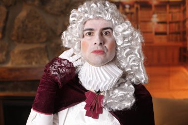 Viktorya tarzı kostümlü genç adam içeride poz veriyor.