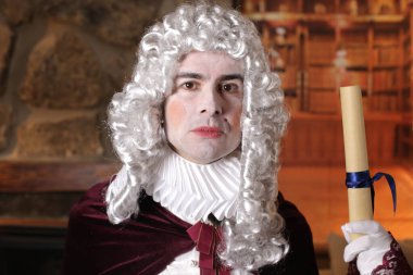 Viktorya tarzı kostüm giymiş genç adam elinde rulo senaryo tutuyor.