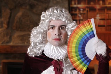 Viktorya tarzı kostümlü genç adam elinde lgbtq renkli yelpaze tutuyor.