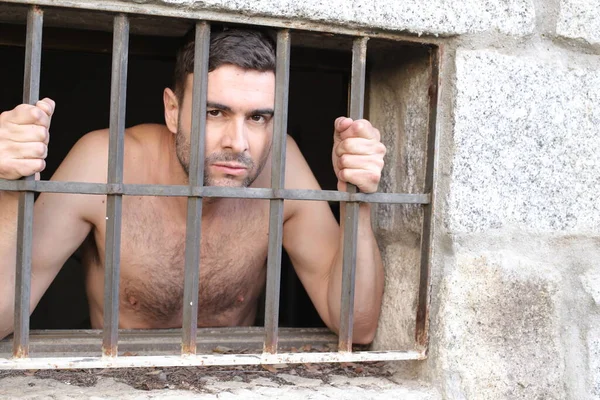 close-up portrait of suffering young man in jail behind cage