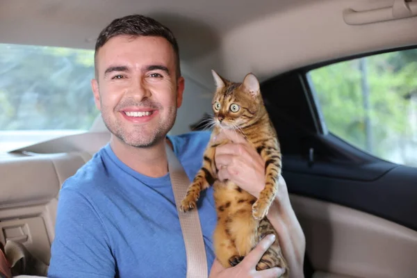 close-up portrait of handsome young man with beautiful cat on back seat of car