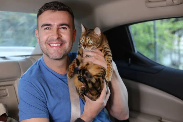 close-up portrait of handsome young man with beautiful cat on back seat of car