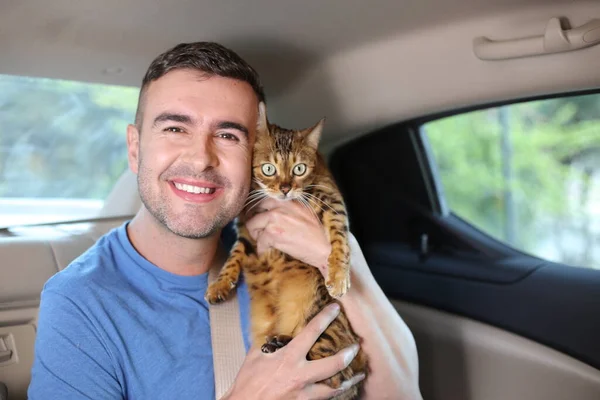 close-up portrait of handsome young man with beautiful cat on back seat of car
