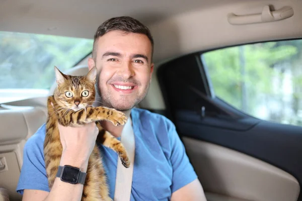 close-up portrait of handsome young man with beautiful cat on back seat of car
