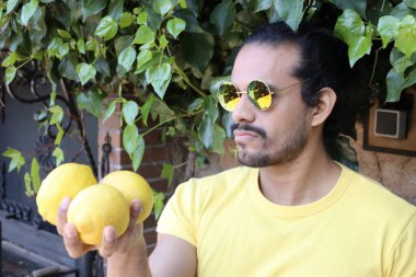 Açık havada limonlu sarı tişörtlü yakışıklı genç adamın portresi.