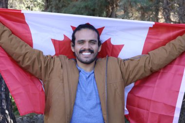 Sokakta Kanada bayrağı taşıyan yakışıklı genç adamın portresi.