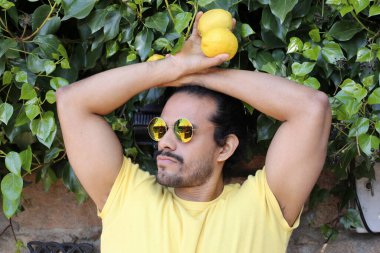 Açık havada limonlu sarı tişörtlü yakışıklı genç adamın portresi.