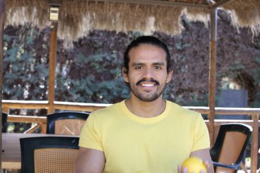 Açık havada limonlu sarı tişörtlü yakışıklı genç adamın portresi.