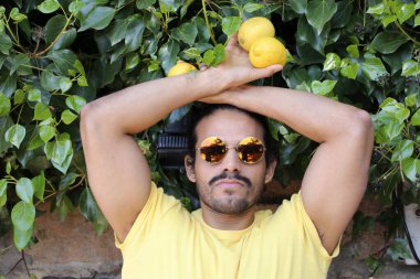 Açık havada limonlu sarı tişörtlü yakışıklı genç adamın portresi.