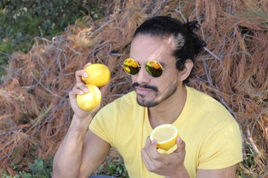 Açık havada limonlu sarı tişörtlü yakışıklı genç adamın portresi.