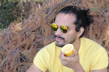 Açık havada limonlu sarı tişörtlü yakışıklı genç adamın portresi.