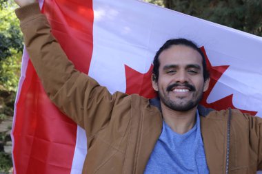 Sokakta Kanada bayrağı taşıyan yakışıklı genç adamın portresi.
