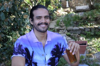 Mor gömlekli yakışıklı bir genç adam ve açık havada bira şişesi.