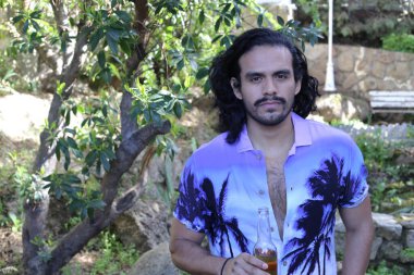 Mor gömlekli yakışıklı bir genç adam ve açık havada bira şişesi.