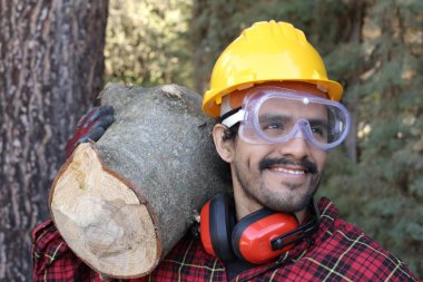 Kasklı yakışıklı oduncunun portresi omuzunda kütük tutuyor.