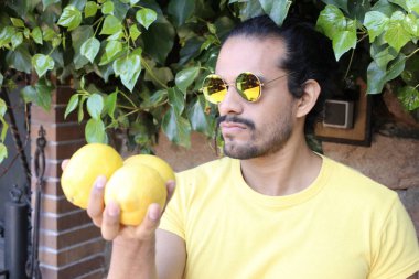 Açık havada limonlu sarı tişörtlü yakışıklı genç adamın portresi.