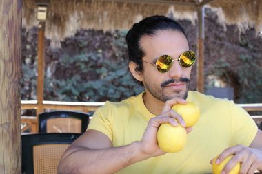 Açık havada limonlu sarı tişörtlü yakışıklı genç adamın portresi.