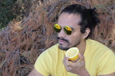 Açık havada limonlu sarı tişörtlü yakışıklı genç adamın portresi.