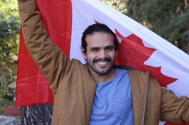 Sokakta Kanada bayrağı taşıyan yakışıklı genç adamın portresi.