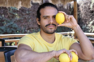 Açık havada limonlu sarı tişörtlü yakışıklı genç adamın portresi.