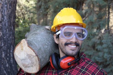 Kasklı yakışıklı oduncunun portresi omuzunda kütük tutuyor.
