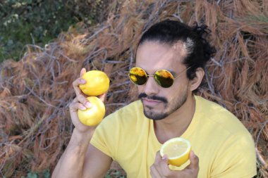 Açık havada limonlu sarı tişörtlü yakışıklı genç adamın portresi.